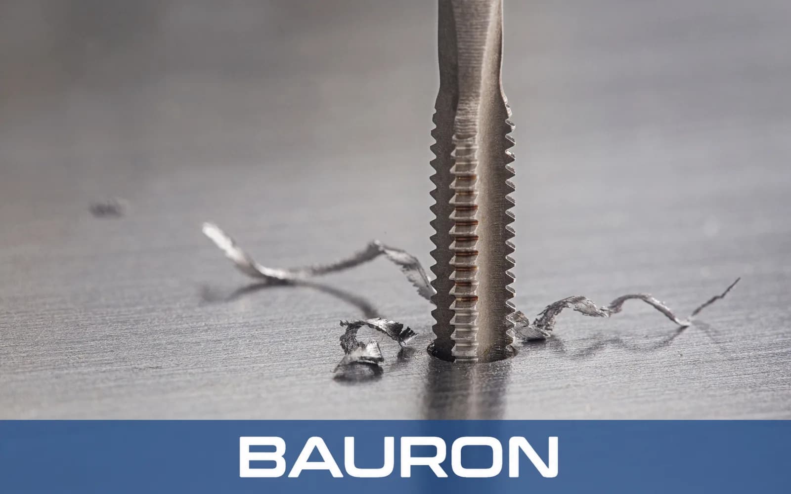 Close-up of a tap threading a hole with curled chips